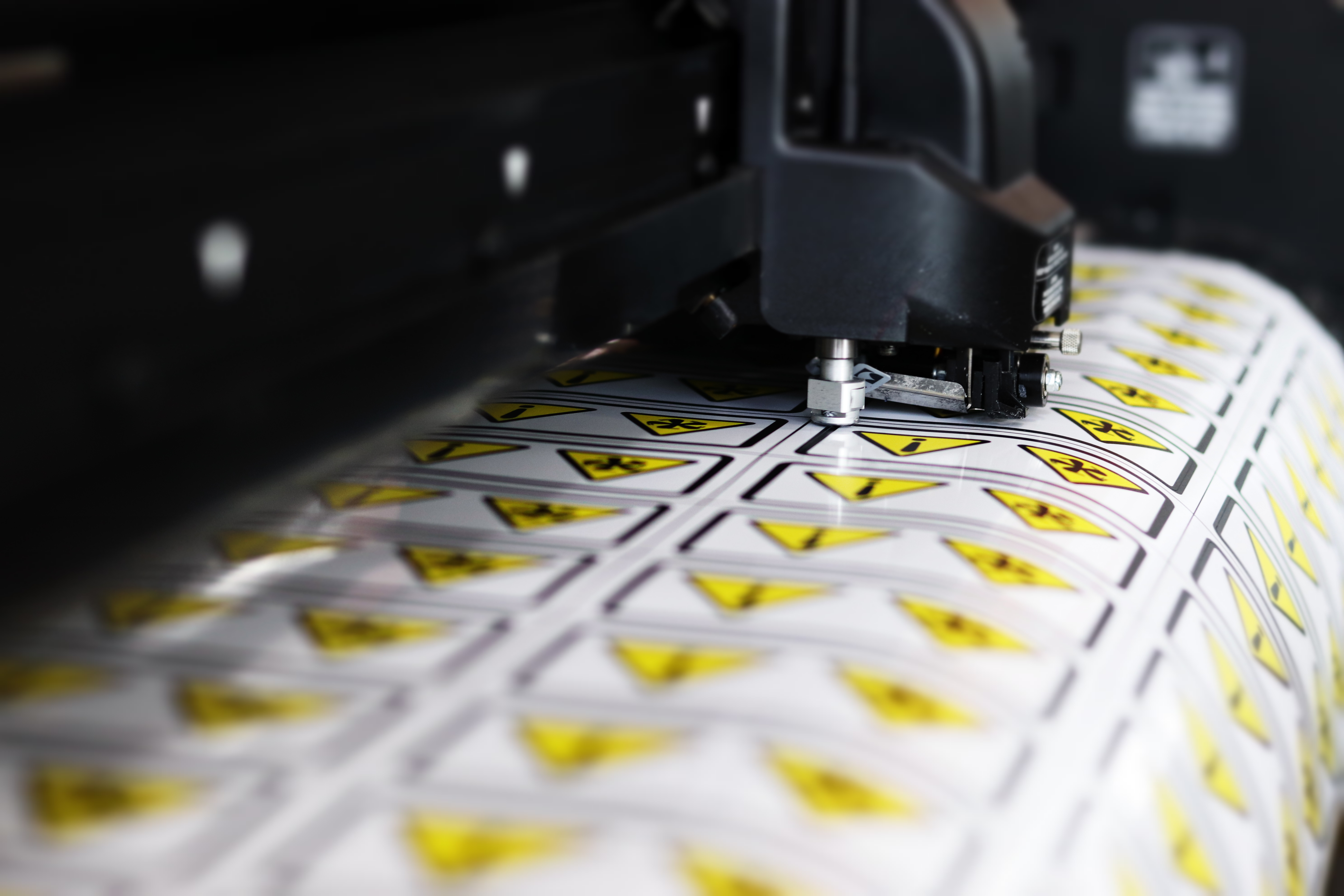 Sheets of yellow warning and safety decals coming off a large-format press