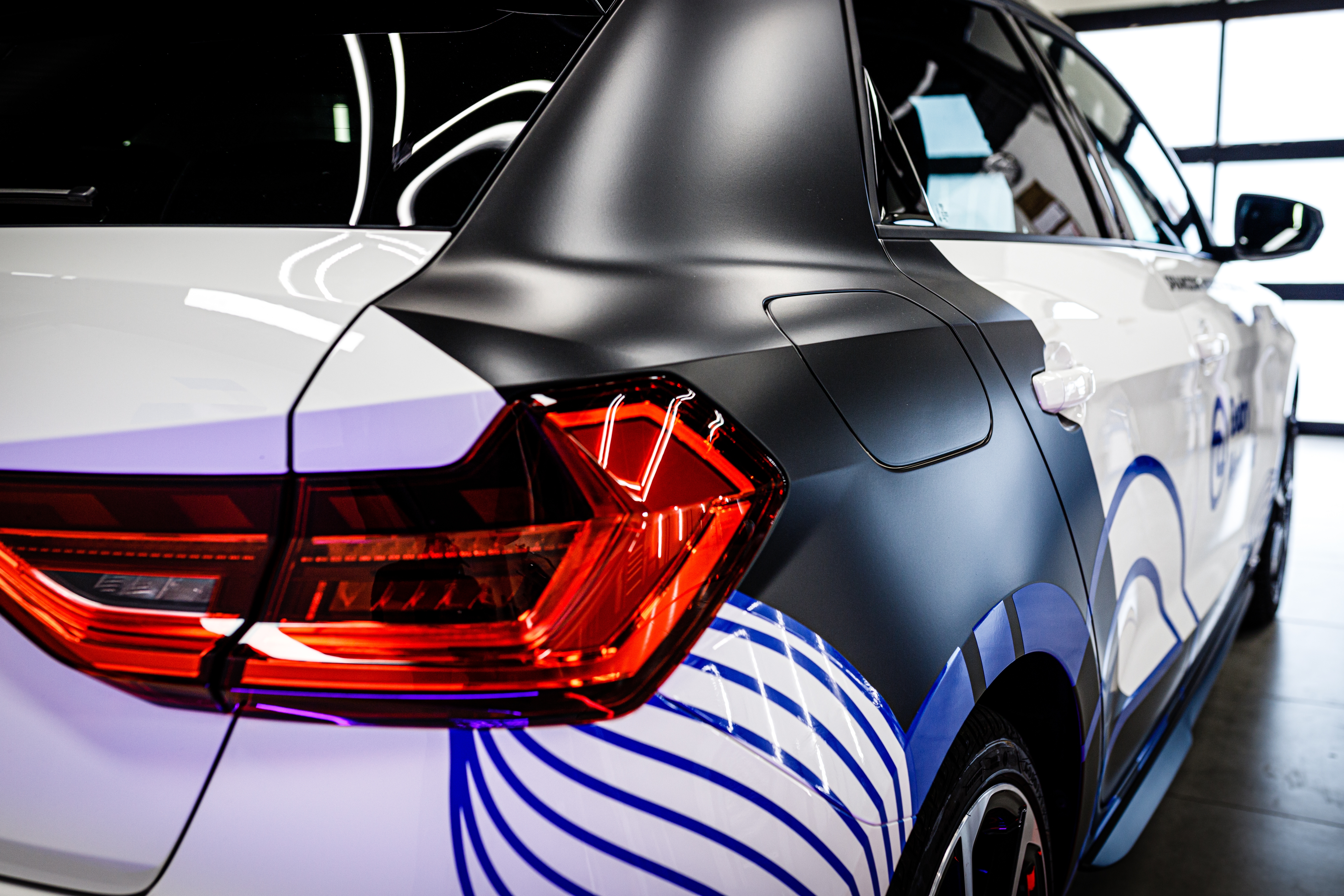 Custom vehicle wrap with matte black and blue line graphics on a car
